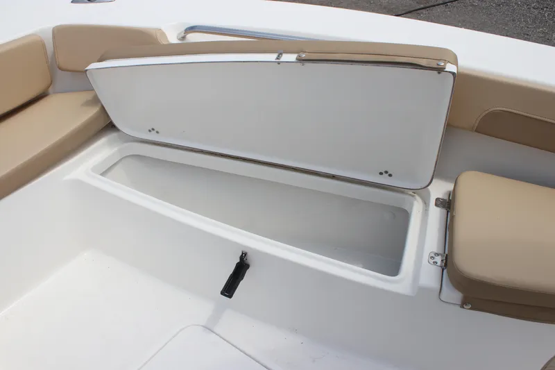 Slide: The Image of 2025 Sea Pro 202 CC boat storage compartment with open lid and beige seating. - 19