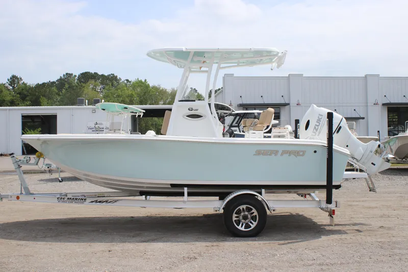 Slide: The Image of 2025 Sea Pro 202 CC boat on trailer, parked outdoors near industrial buildings. - 8