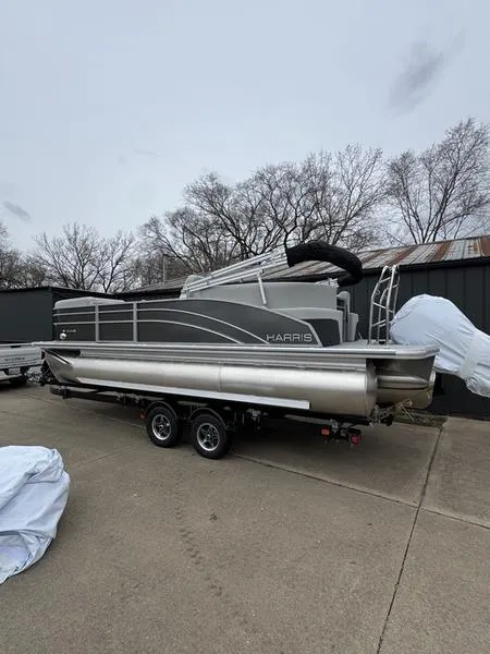 Slide: The Image of 2025 Harris Cruiser 210 pontoon boat on trailer, parked outdoors. - 1