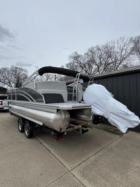 Slide: The Image of 2025 Harris Cruiser 210 pontoon boat on trailer, parked outdoors. - 2