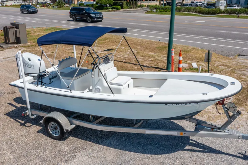 Slide: The Image of 2016 Panga 19 Niente boat on trailer with blue canopy, parked near a road. - 1