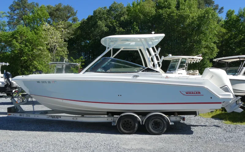 Slide: The Image of 2022 Boston Whaler 240 Vantage boat on trailer, surrounded by greenery. - 2