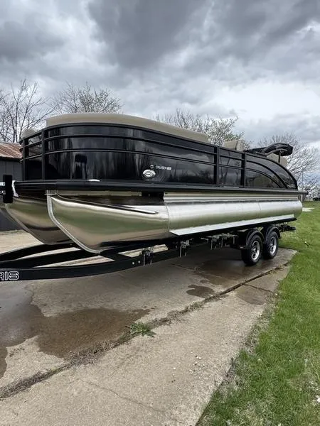 Slide: The Image of 2025 Harris Cruiser 230 pontoon boat on trailer under cloudy sky. - 2
