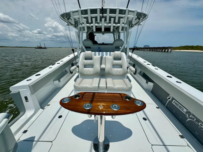 Slide: The Image of 2024 Freeman 38 boat interior with seating and wooden table on calm water. - 35