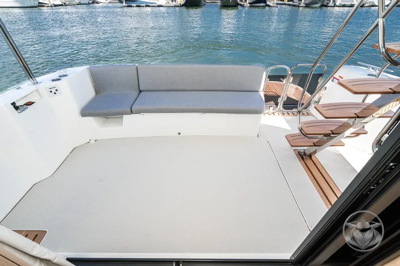 Slide: The Image of 2026 Beneteau Swift Trawler 48 deck with seating and wooden stairs by the water. - 32