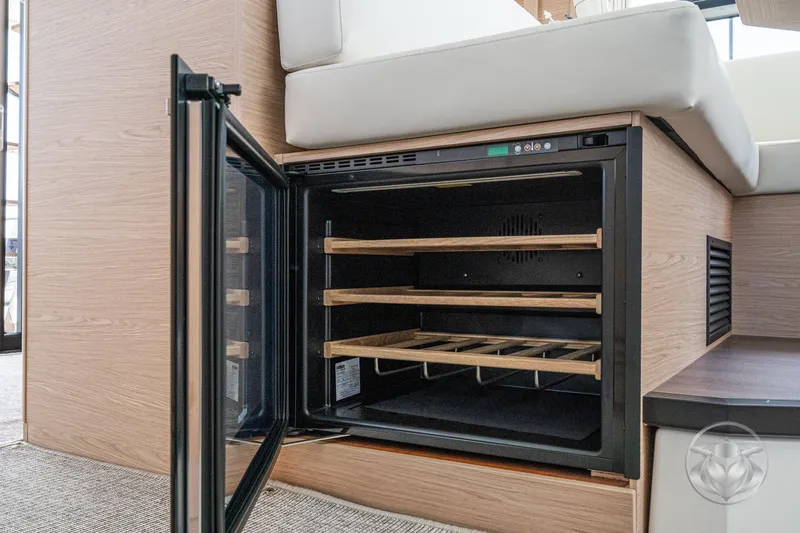 Slide: The Image of 2026 Beneteau Swift Trawler 48 interior with open wine cooler, wooden shelves. - 42