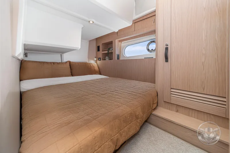 Slide: The Image of 2026 Beneteau Swift Trawler 48 cabin with cozy bed and wooden interior. - 58