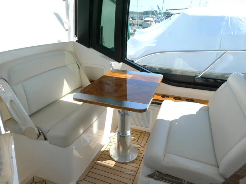 Slide: The Image of 2021 Boston Whaler 405 Conquest interior with white seating and wooden table. - 11
