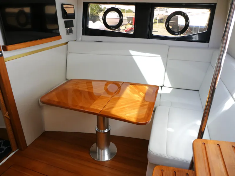 Slide: The Image of Interior of 2021 Boston Whaler 405 Conquest with white seating and wooden table. - 24