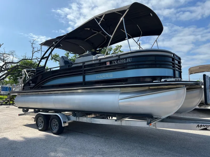 The Image of 2021 Harris FloteBote 230 Solstice pontoon boat on trailer under blue sky. - 0