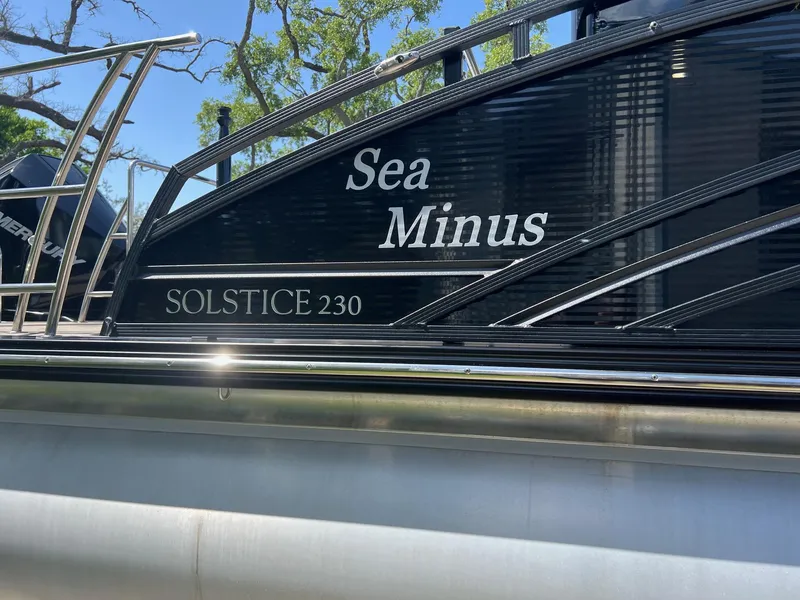 Slide: The Image of 2021 Harris FloteBote 230 Solstice pontoon boat with "Sea Minus" name, docked under blue sky. - 2