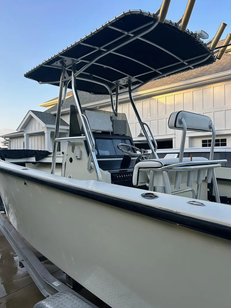 Slide: The Image of 1985 SeaCraft 23 CC boat with T-top and dual seats, docked near a house. - 8