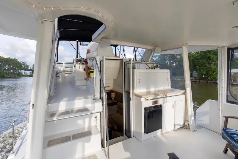 Slide: The Image of 1997 Carver 445 Aft Cabin Motor Yacht interior with stairs and kitchenette, docked by a river. - 17