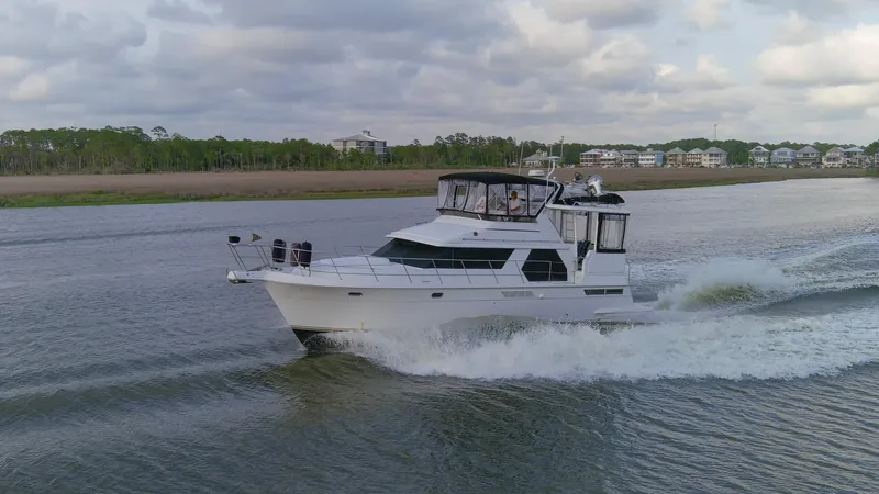 Slide: The Image of 1997 Carver 445 Aft Cabin Motor Yacht cruising on a calm river under cloudy skies. - 23