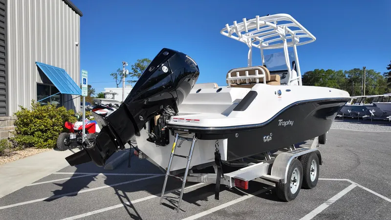 Slide: The Image of 2025 Bayliner Trophy 24 CC boat on trailer, parked outdoors, with outboard motor. - 4