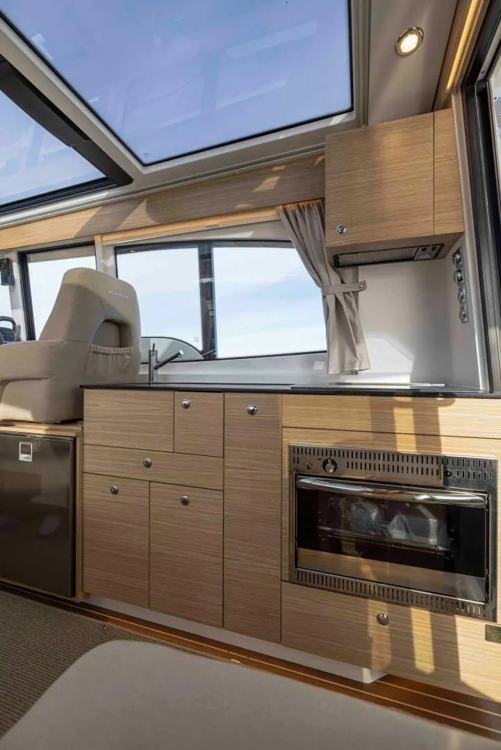 Slide: The Image of Interior of 2025 Nimbus 365 Coupe, featuring modern kitchen with wood cabinetry and skylight. - 8