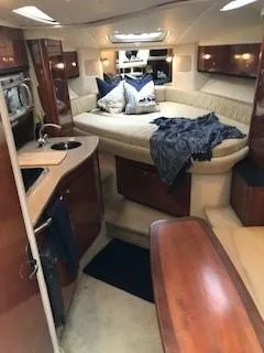 Slide: The Image of 2007 Sea Ray 310 Sundancer interior with cozy seating, kitchenette, and elegant wood finishes. - 12