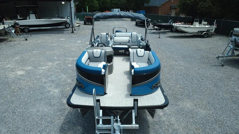 Slide: The Image of 2025 Tahoe Pontoon LTZ Versatile Rear Lounger, blue and gray, parked on gravel lot. - 28