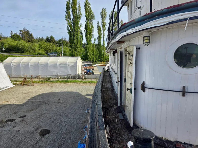 Slide: The Image of Historic 1890 custom tugboat docked, surrounded by trees and a white tent structure. - 10