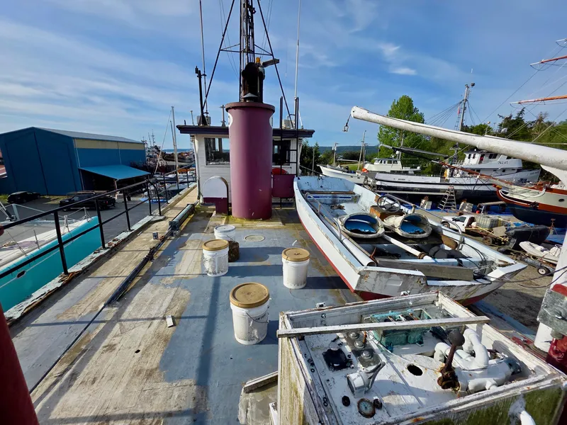 Slide: The Image of Historic 1890 custom tugboat deck with equipment, docked in a marina under a clear blue sky. - 21
