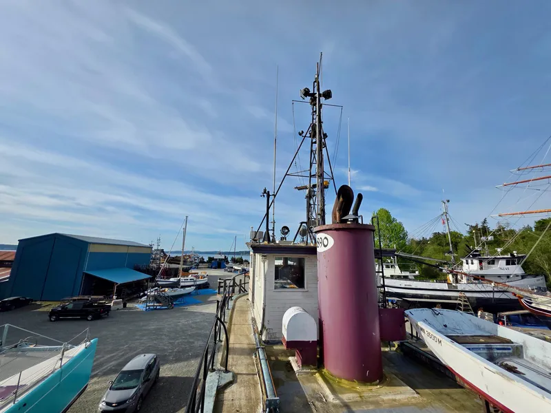 Slide: The Image of Historic 1890 custom tugboat docked at a busy shipyard under a clear blue sky. - 23