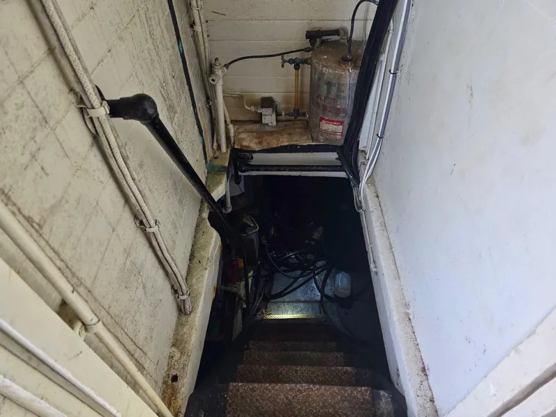 Slide: The Image of Narrow stairway leading to engine room of 1890 custom tugboat, with visible pipes and machinery. - 25