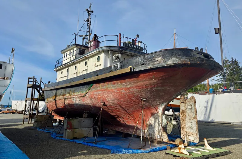 Slide: The Image of Historic 1890 custom tugboat on dry dock for restoration under clear blue sky. - 3