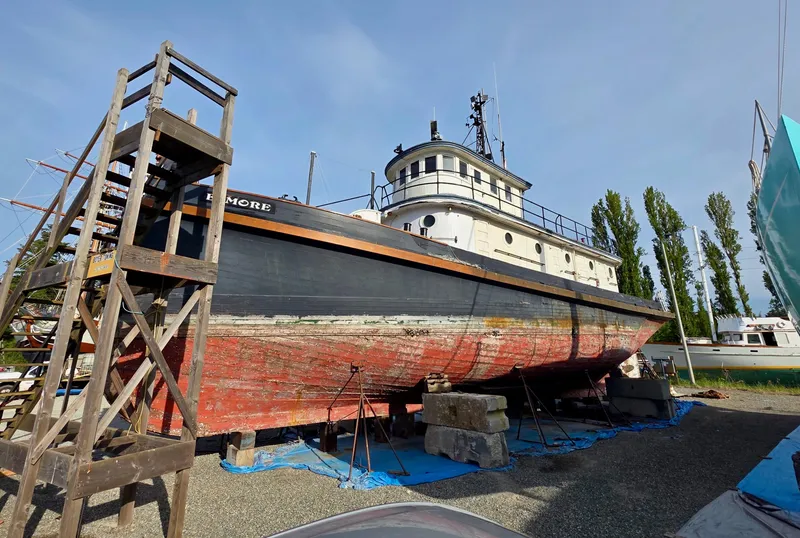 Slide: The Image of Vintage 1890 custom tugboat on dry dock with weathered hull and wooden ladder. - 4