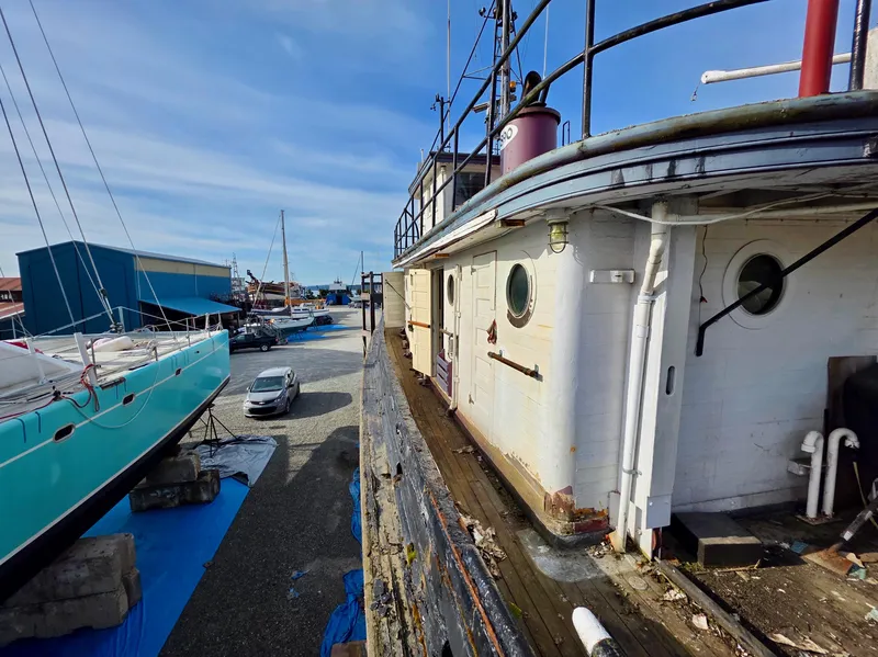 Slide: The Image of Restored 1890 custom tugboat docked beside modern yachts in a shipyard. - 43