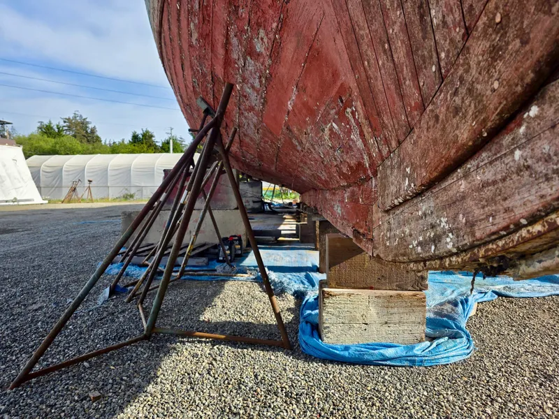 Slide: The Image of Historic 1890 custom tugboat under restoration, supported by metal stands on gravel. - 45
