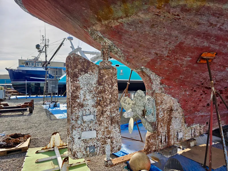 Slide: The Image of Historic 1890 custom tugboat under repair, showcasing aged propeller and rudder in a shipyard. - 48