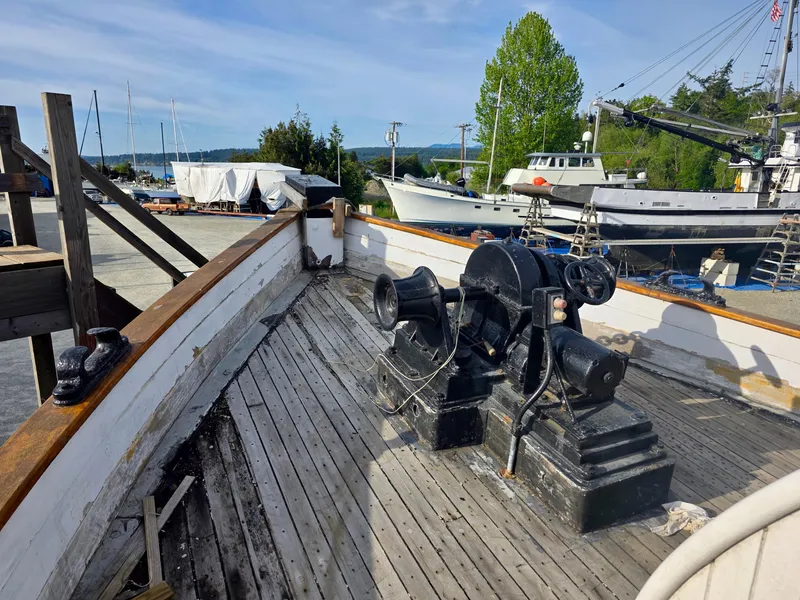 Slide: The Image of Historic 1890 custom tugboat deck with winch, docked near other boats, under clear sky. - 7