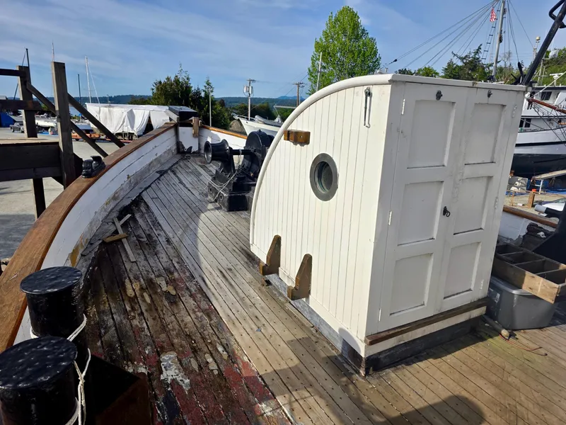Slide: The Image of Restored 1890 custom tugboat deck with wooden cabin and porthole, docked outdoors. - 8
