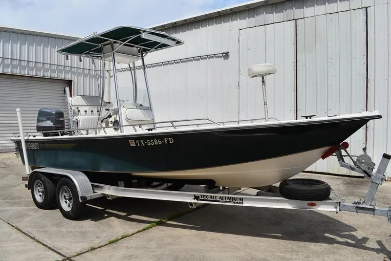 Slide: The Image of 1998 Kenner 21V CC Tunnel boat on trailer, parked outside a warehouse. - 1