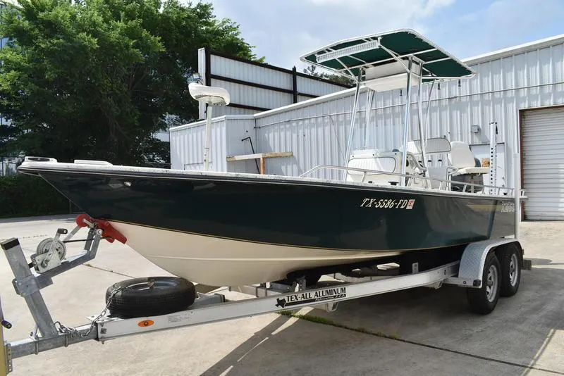 Slide: The Image of 1998 Kenner 21V CC Tunnel boat on trailer, parked outdoors near a metal building. - 3