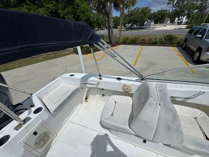 Slide: The Image of 2001 Boston Whaler 18 Ventura boat interior with seating and canopy in parking lot. - 25