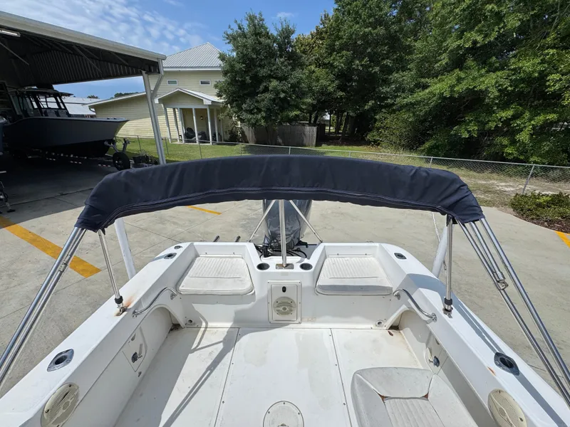 Slide: The Image of 2001 Boston Whaler 18 Ventura boat with canopy, parked outdoors near trees and buildings. - 27