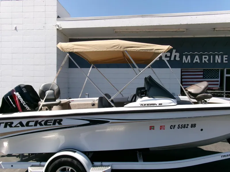 Slide: The Image of 2005 Tracker Tundra 18 DC boat with canopy, parked outside a marine shop. - 30