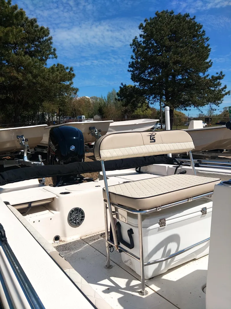 Slide: The Image of 2022 Carolina Skiff 19 LS boat with seating, parked outdoors under a clear blue sky. - 5