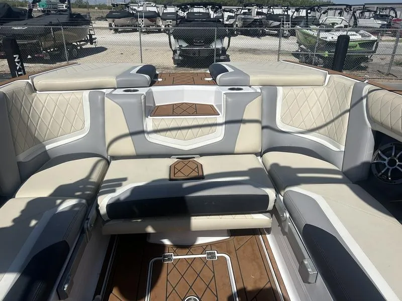 Slide: The Image of 2019 Tigé ZX5 boat interior with beige and gray seating, diamond stitching, and wood accents. - 2
