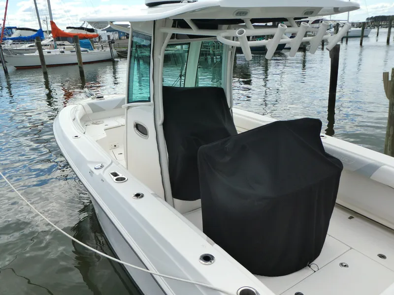 Slide: The Image of 2016 Boston Whaler 250 Outrage boat docked, featuring covered seats and fishing rod holders. - 3