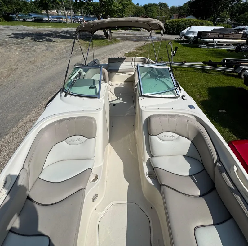 Slide: The Image of 2003 Sea Ray 240 Sundeck boat with spacious seating and canopy, docked outdoors. - 12