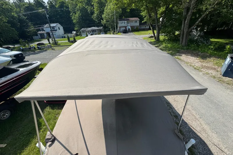 Slide: The Image of 2003 Sea Ray 240 Sundeck with beige canopy, parked outdoors. - 17