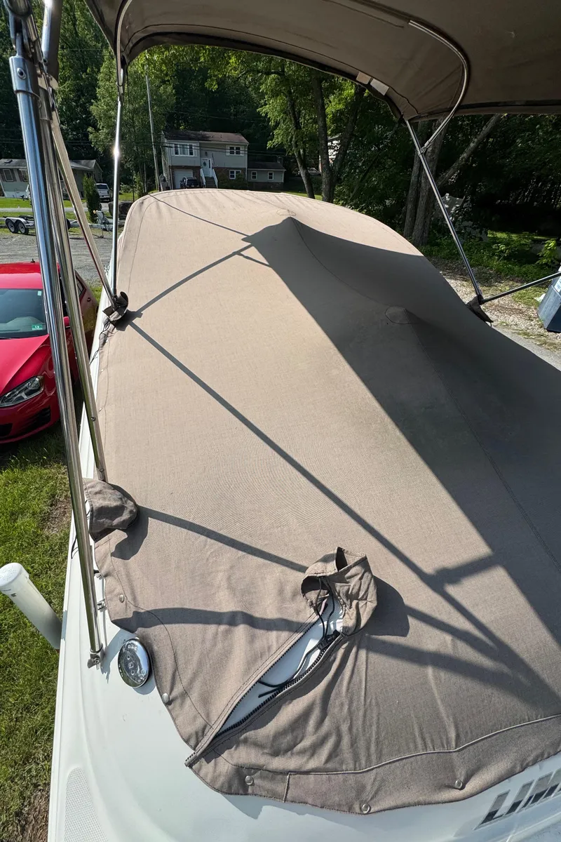 Slide: The Image of 2003 Sea Ray 240 Sundeck covered with a beige canopy, parked outdoors. - 19
