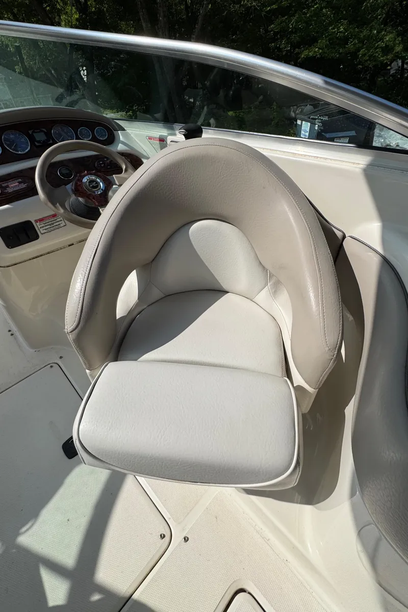 Slide: The Image of 2003 Sea Ray 240 Sundeck boat interior with steering wheel and cushioned seat. - 9