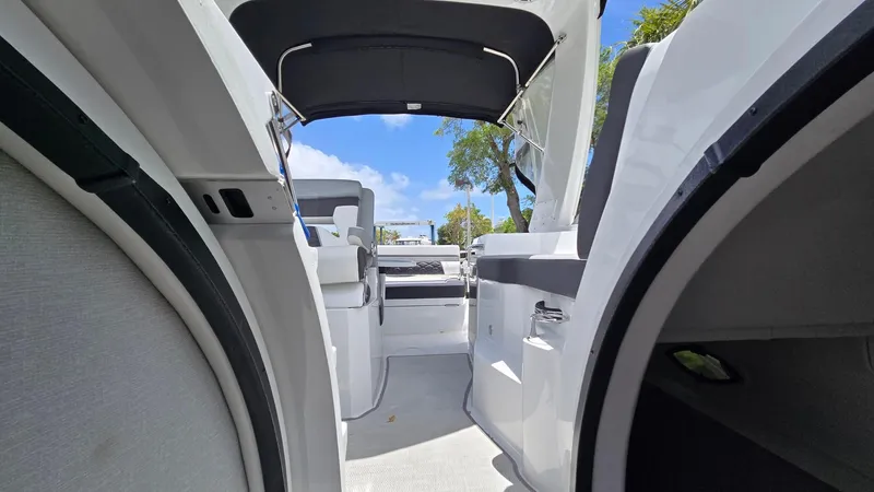 Slide: The Image of 2022 Monterey 295SY boat interior with open cabin and seating, under a clear blue sky. - 13