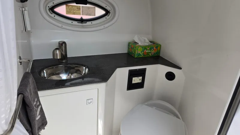 Slide: The Image of 2022 Monterey 295SY boat bathroom with sink, toilet, and oval window. - 18