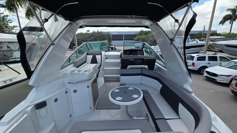Slide: The Image of 2022 Monterey 295SY boat interior with seating and table, docked at a marina. - 7