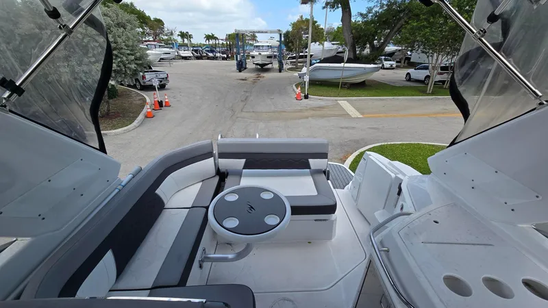 Slide: The Image of 2022 Monterey 295SY boat interior with seating and table, docked at a marina. - 8