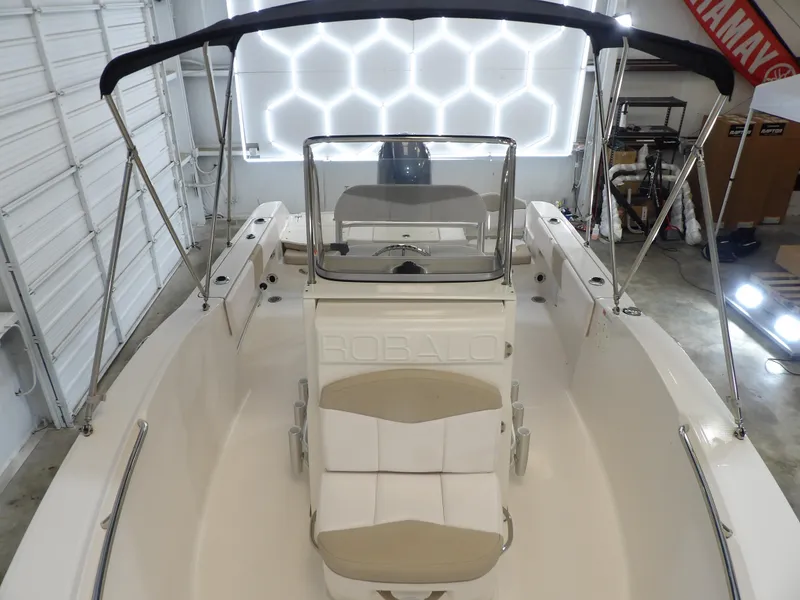 Slide: The Image of 2020 Robalo R180 boat interior with seating and canopy in a garage setting. - 11